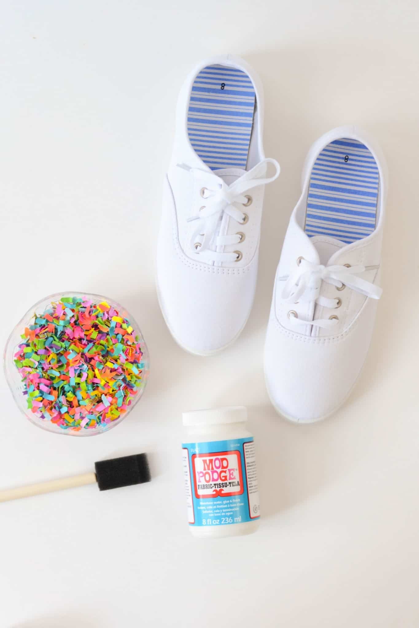 Bowl of confetti, white shoes, Mod Podge Fabric, and a foam brush