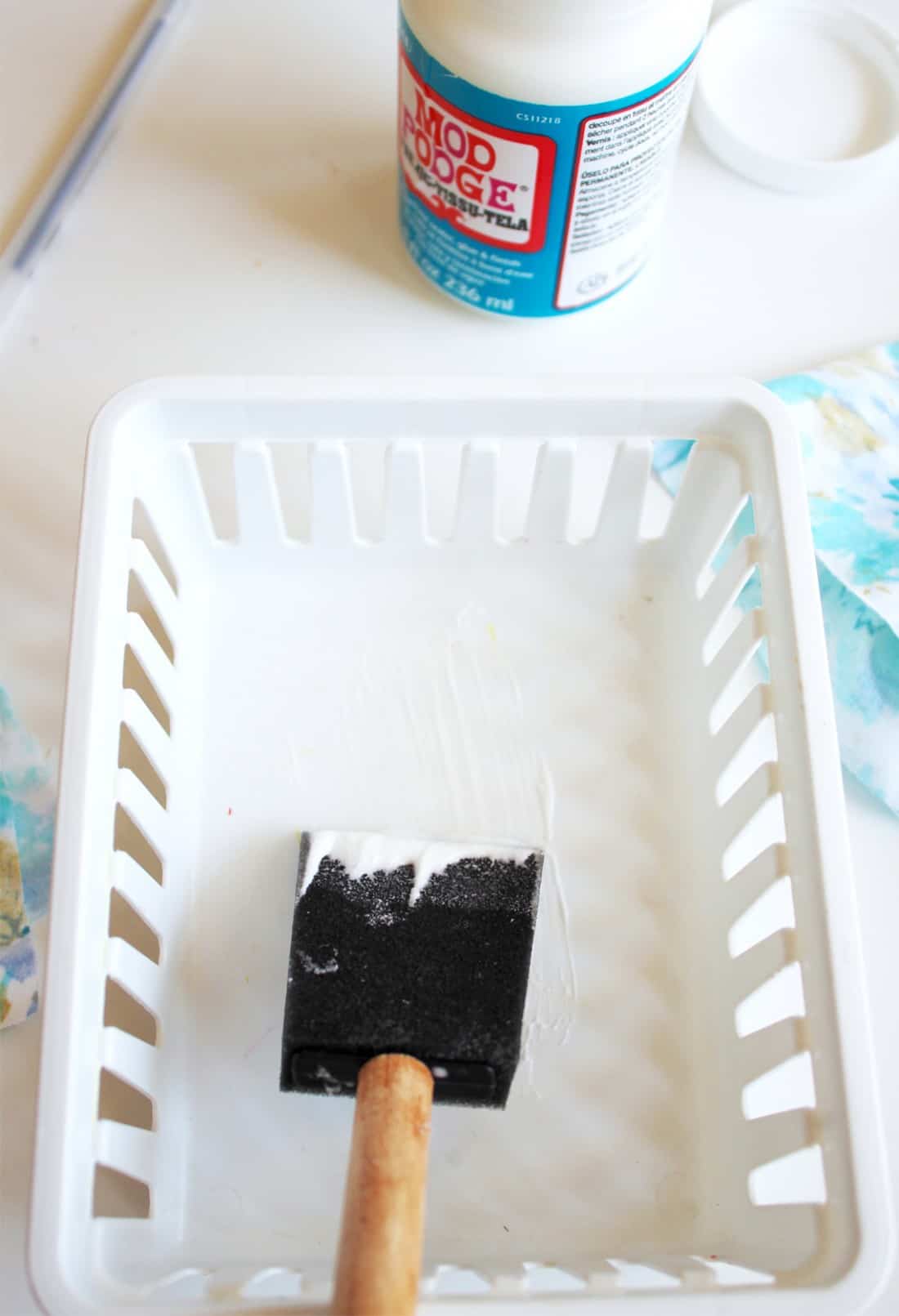 Applying Mod Podge to the inside of a plastic tray
