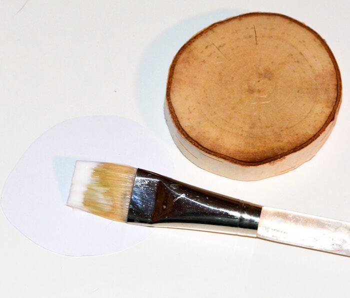 Wood slice and a paintbrush with Mod Podge at the end