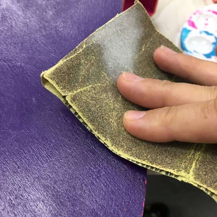 Sanding the edges with a piece of sandpaper to reveal the pink underneath