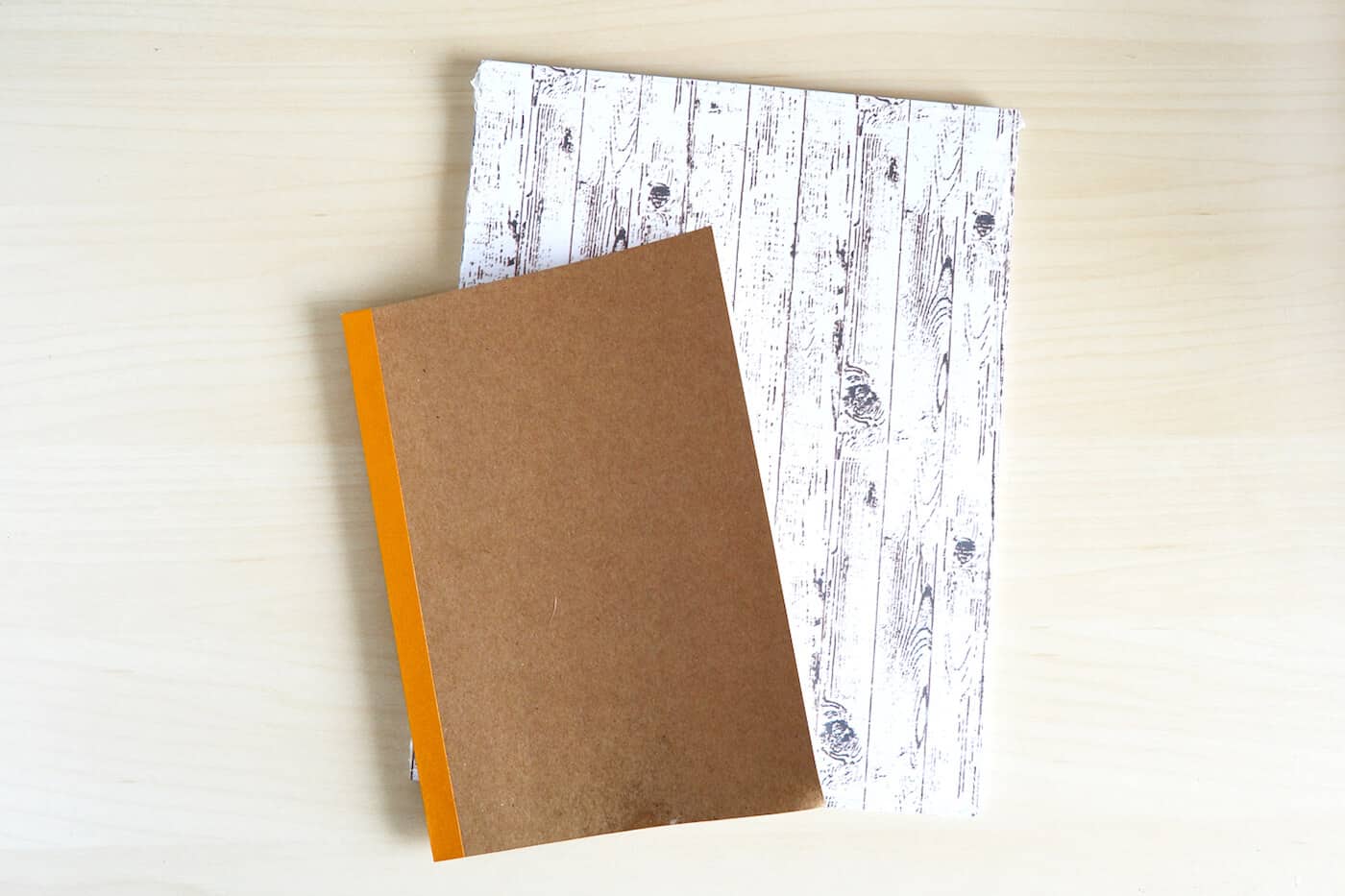 Plain notebook and a piece of paper with a whitewashed wood pattern on it