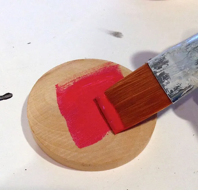 Painting a wood circle with red acrylic paint