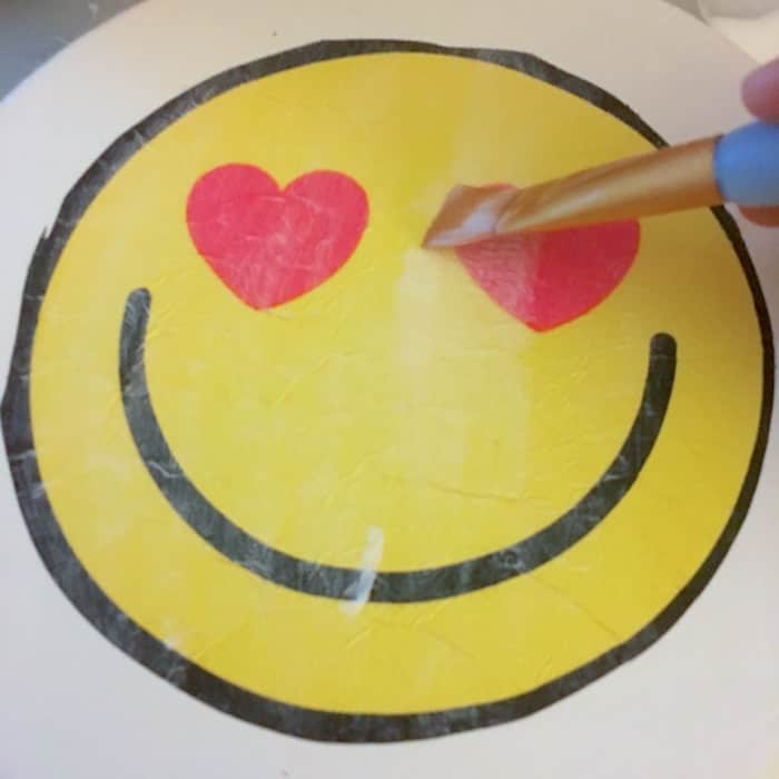 Mod Podging over the top of an emoji napkin on canvas