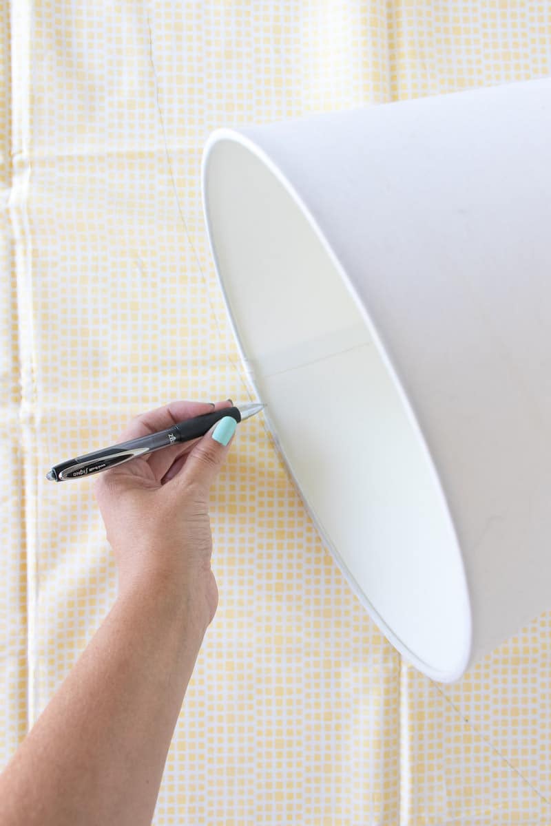 Tracing a lampshade on a piece of fabric with a pen