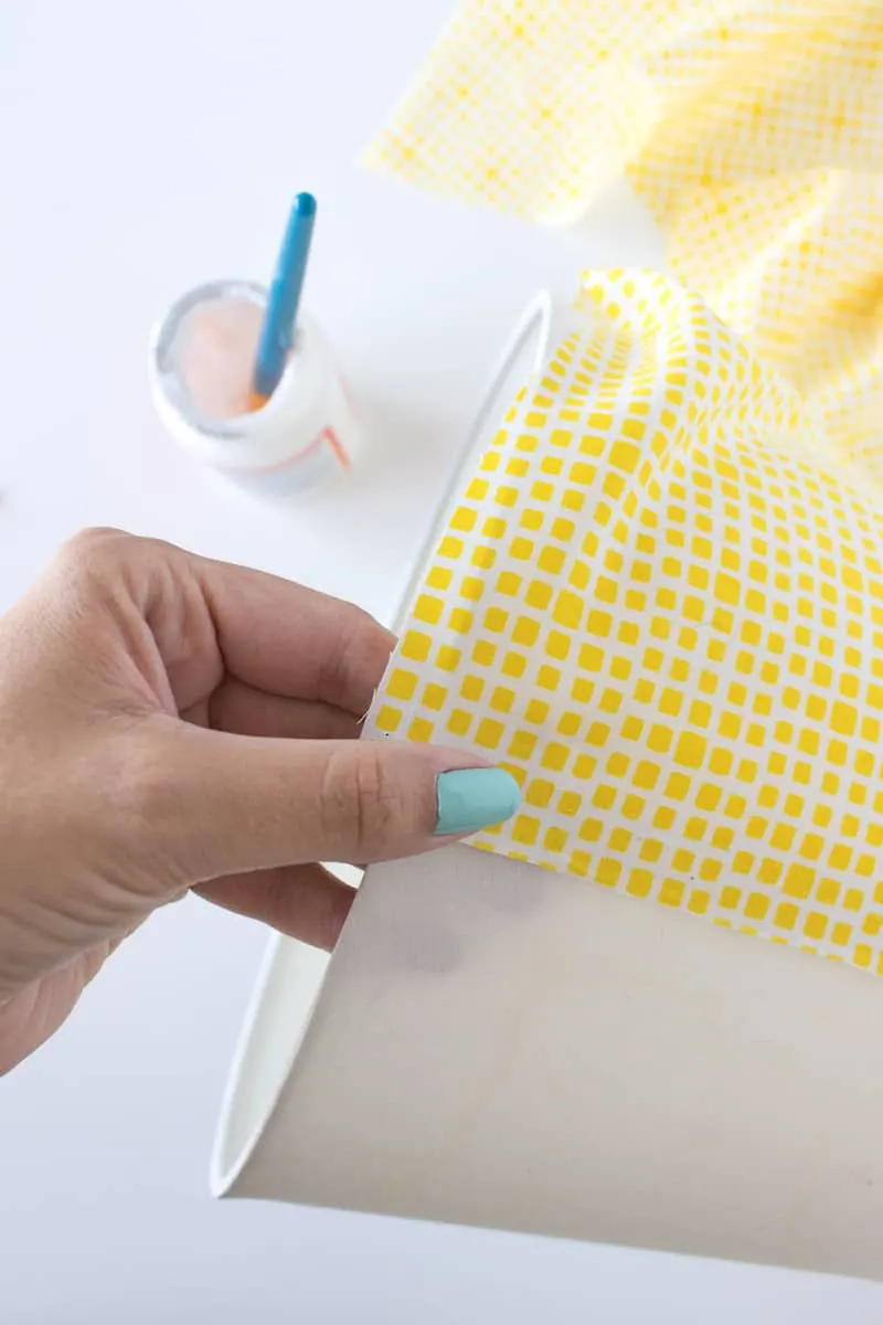 Smoothing fabric down on a lamp shade with Mod Podge