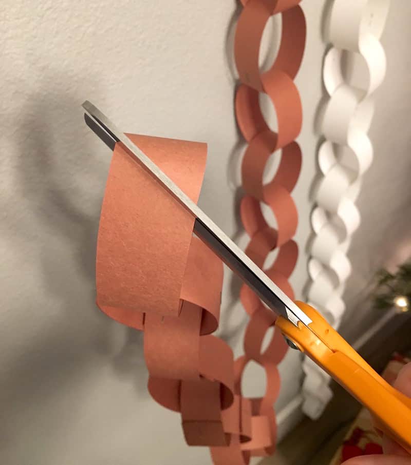 Cutting the rings on a kids paper chain Christmas countdown using a pair of scissors