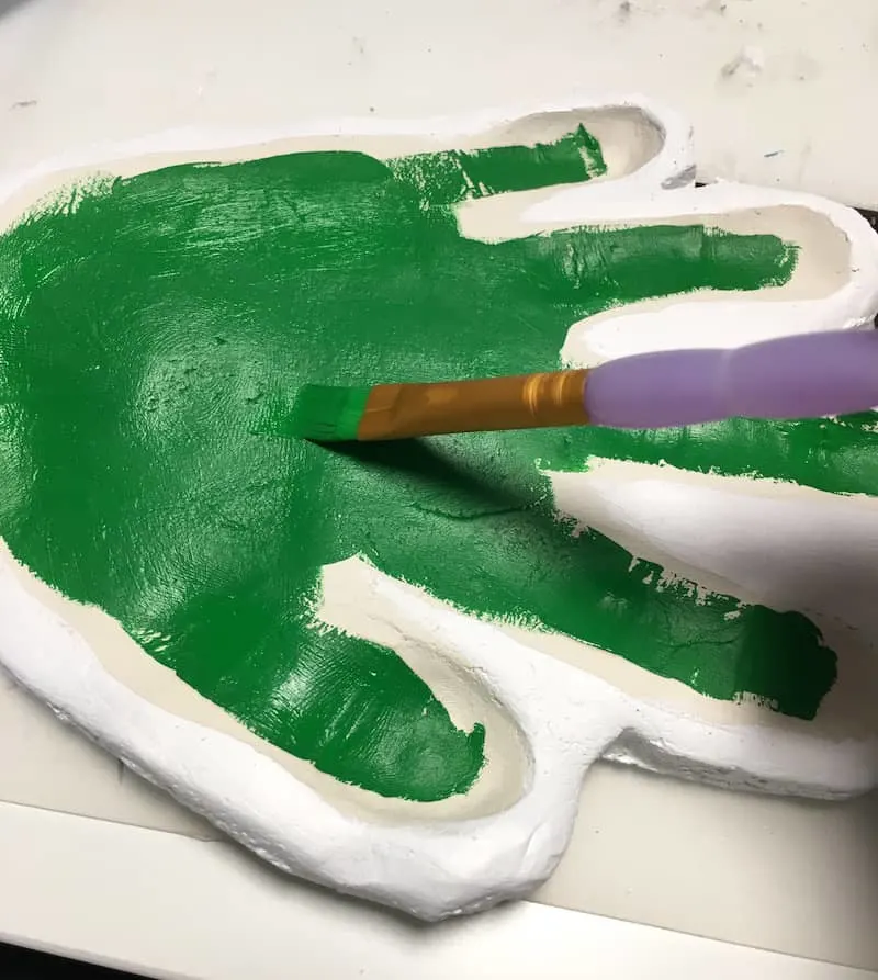 Painting a handprint ornament with green acrylic paint