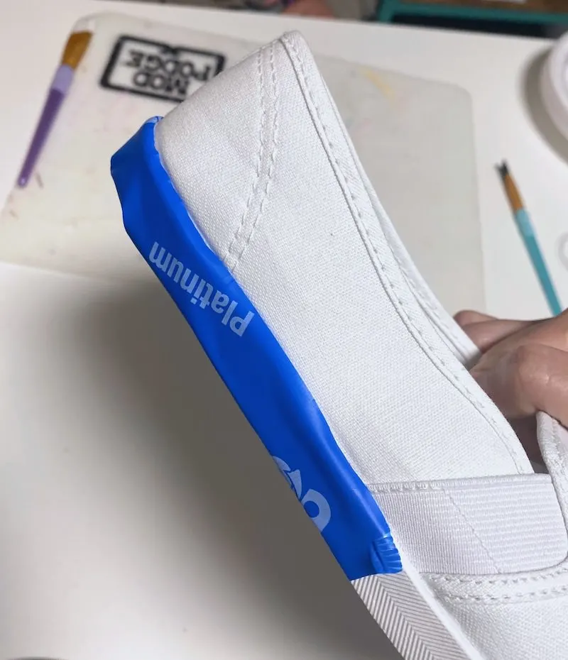 Lining a white canvas shoe with painter's tape