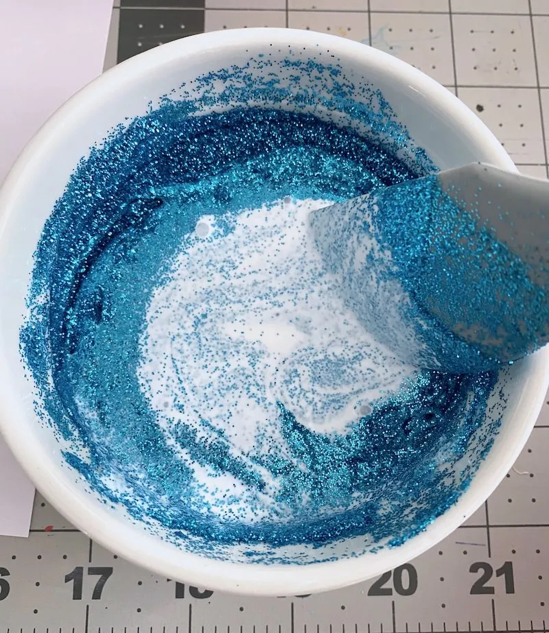 Stirring glitter into a container with Mod Podge