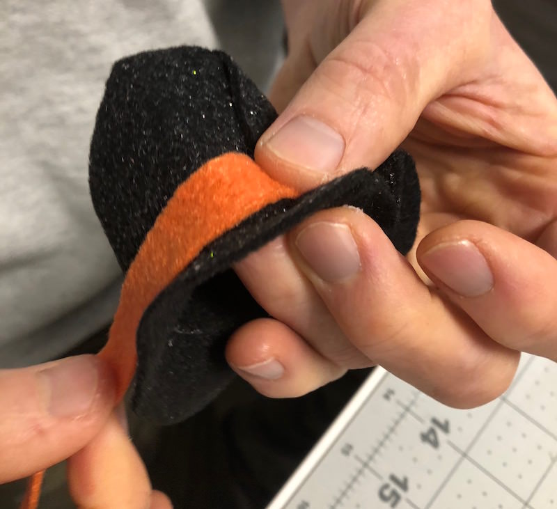 Gluing an orange band of felt around the top of the hat
