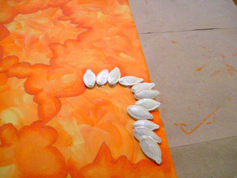 Glue the pumpkin seeds to the canvas