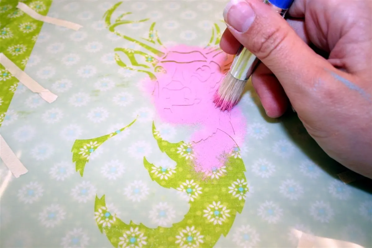 Stenciling a deer silhouette on fabric with pink paint