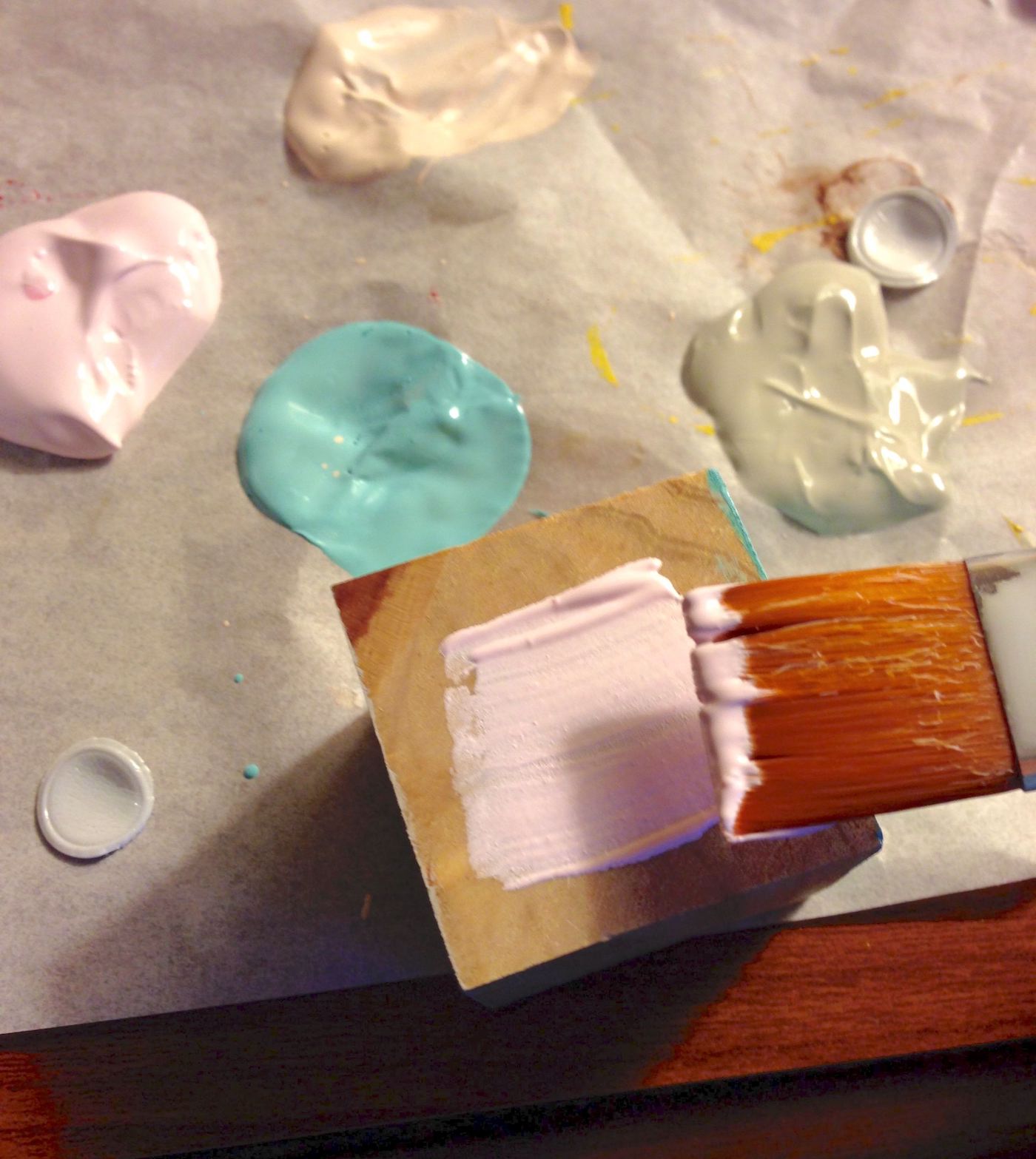 Painting one side of a wood block with pink acrylic paint
