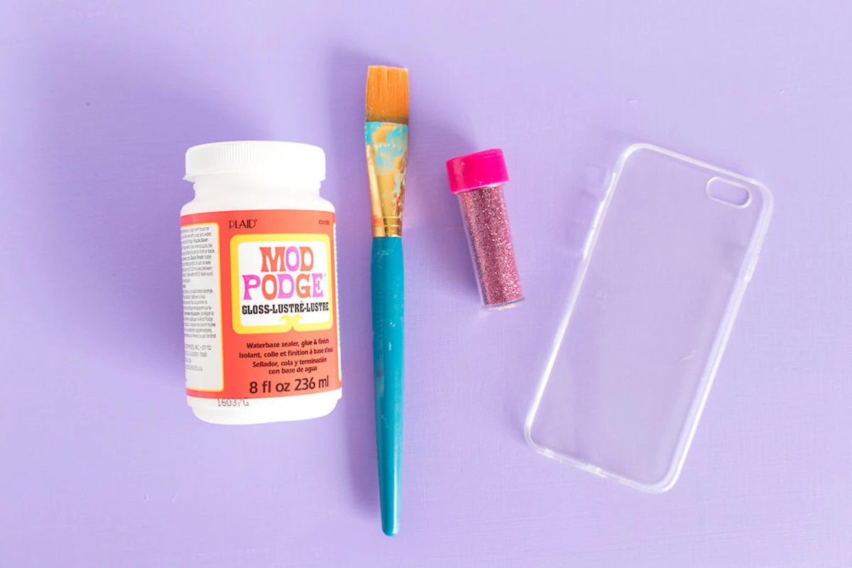 Clear phone case, Mod Podge Gloss, paintbrush, and pink glitter