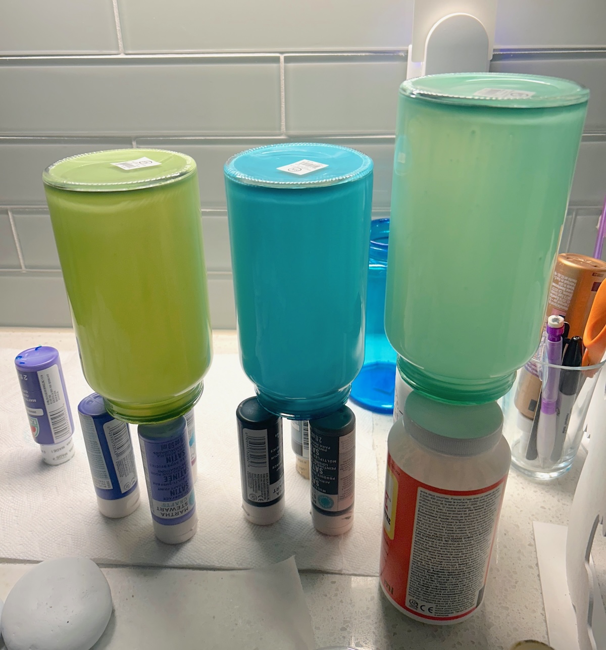 stained glass jars drying on top of paint bottles