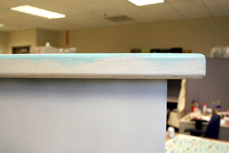 Blue paint going over the edge of wood table