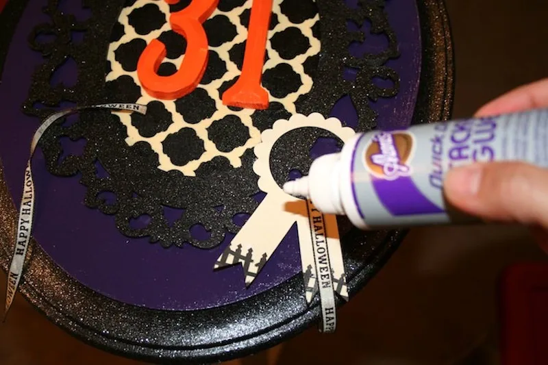 Glue accents onto Halloween wall decor with tacky glue