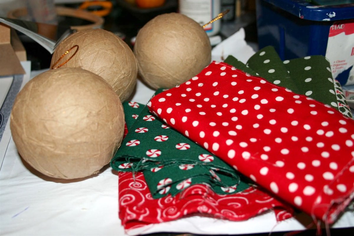 Paper mache christmas ornaments and a pile of Christmas fabric