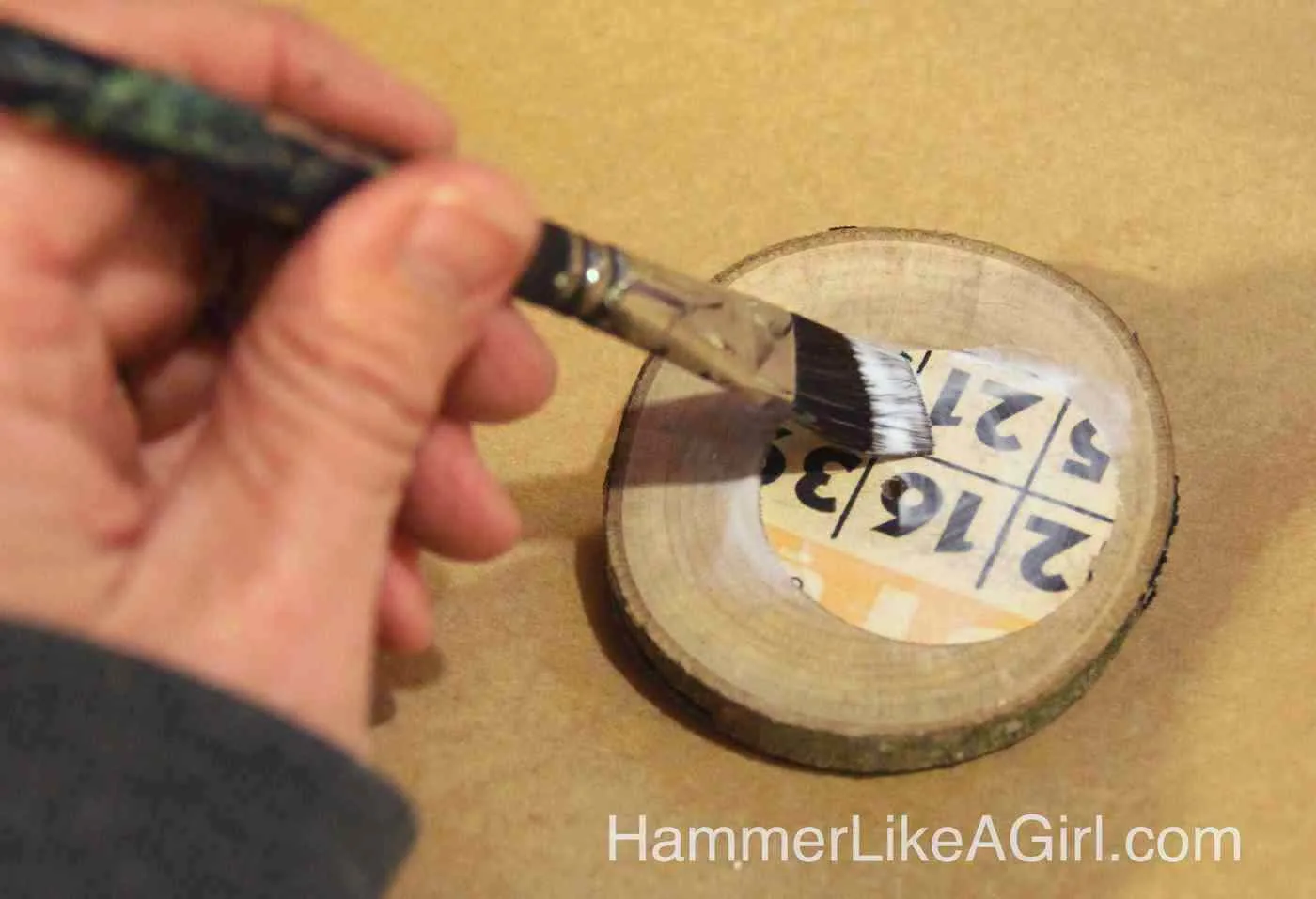 Mod Podge paper down onto wood slices with a paintbrush