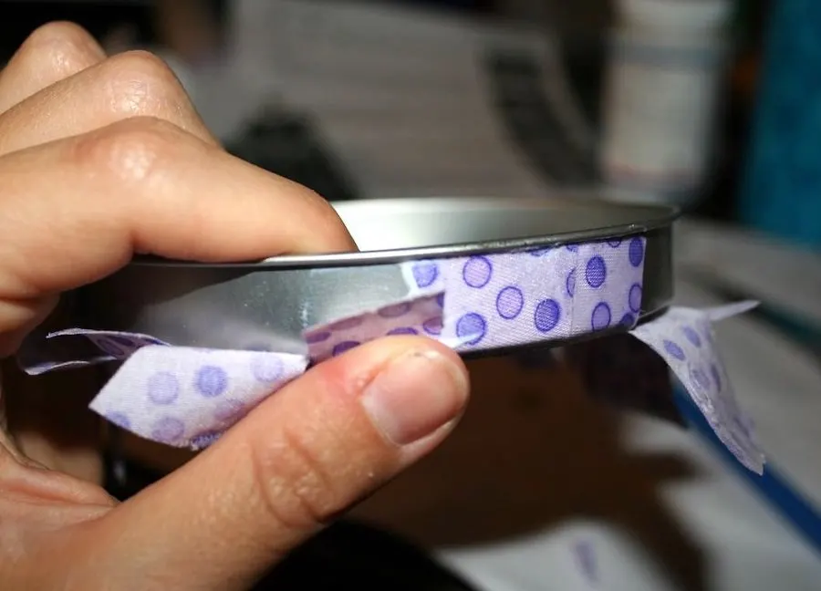 Mod Podging fabric around the edge of a cookie tin lid
