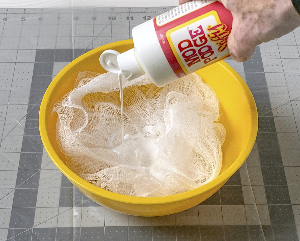 Pouring fabric stiffener over cheesecloth in a bowl