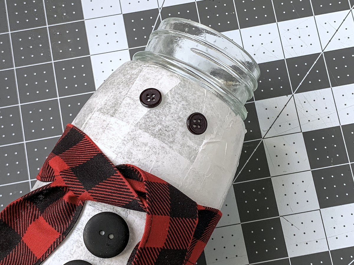 Button eyes glued onto a snowman jar