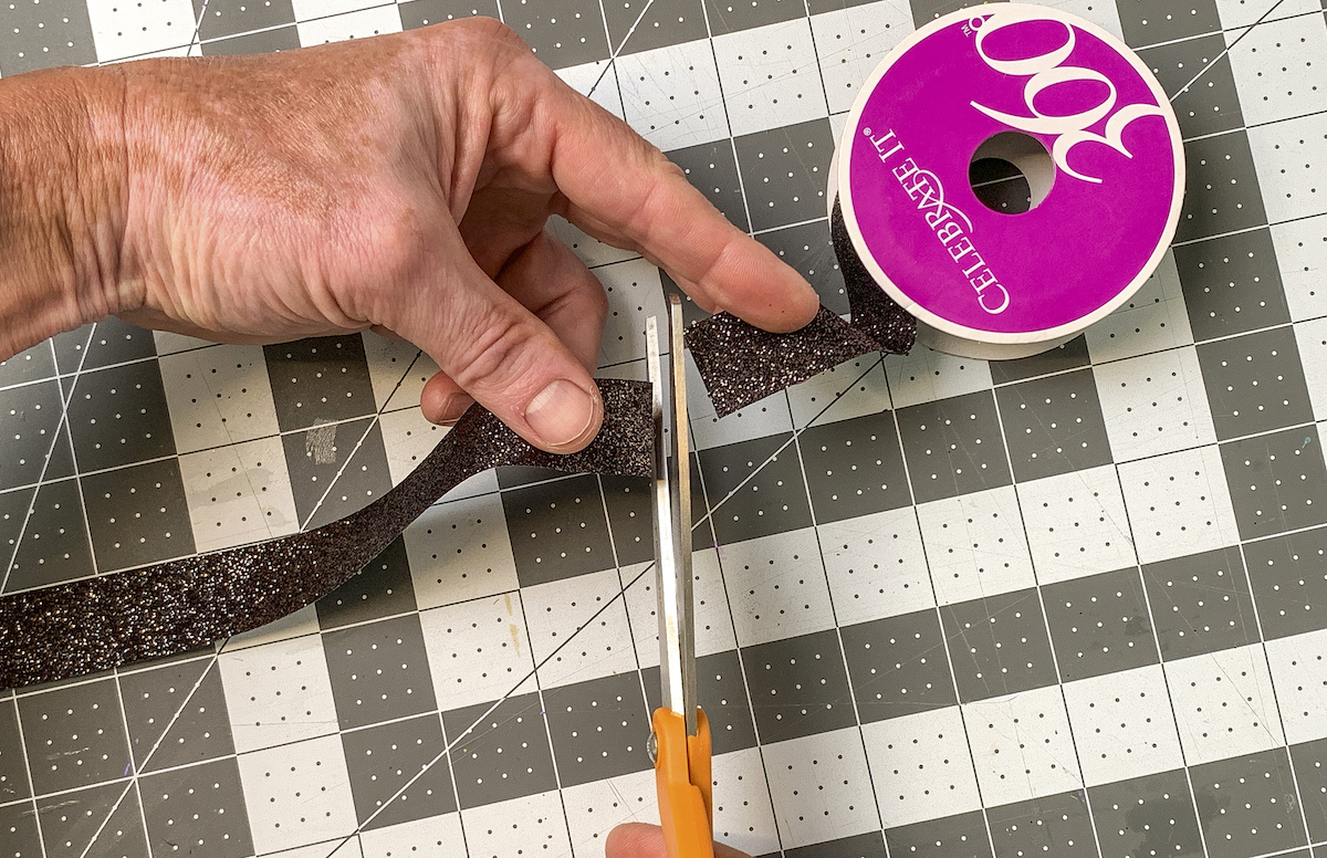Cutting a piece of sparkly black ribbon from a spool