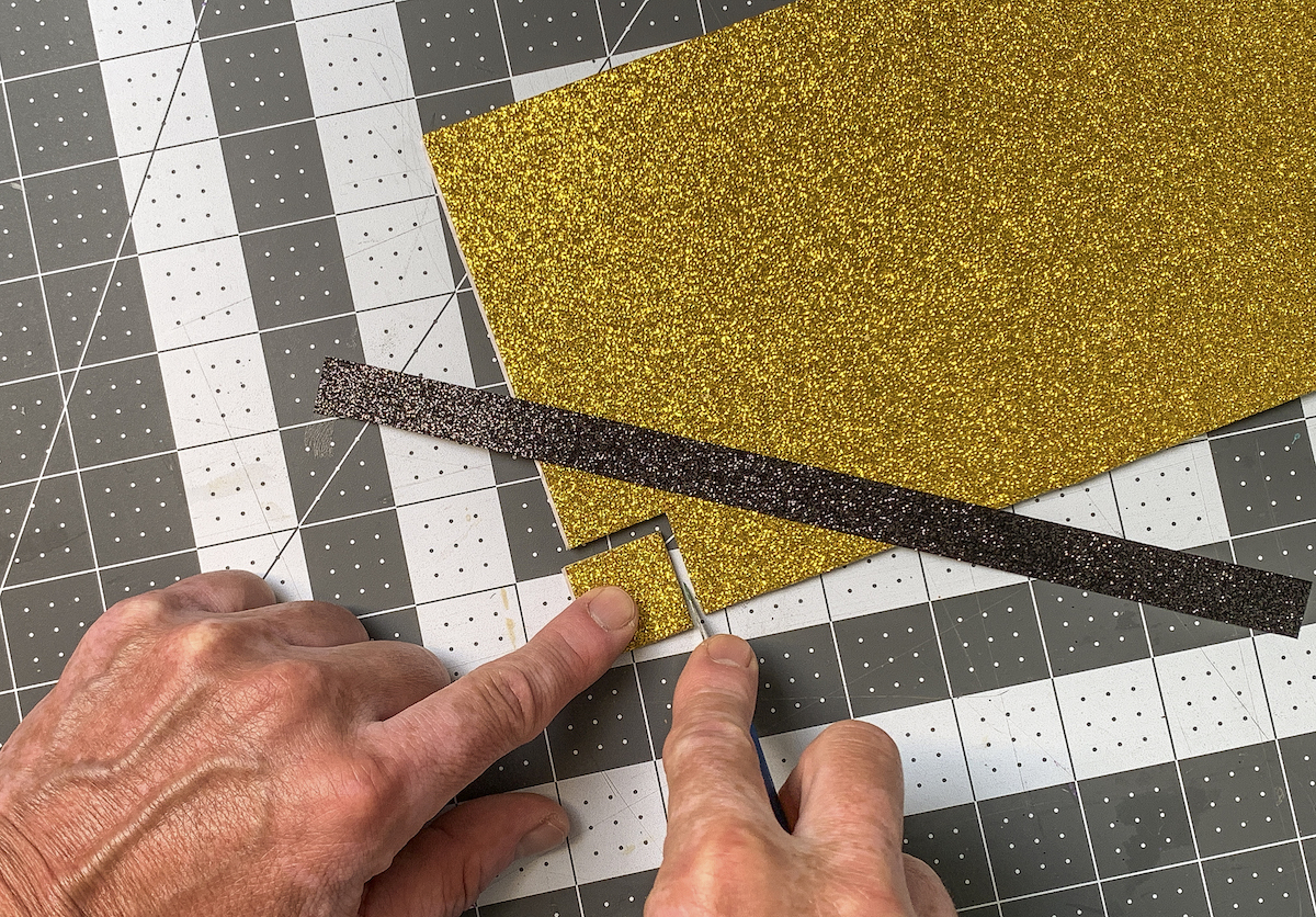 Cortando um pequeno quadrado de espuma dourada brilhante com uma faca artesanal