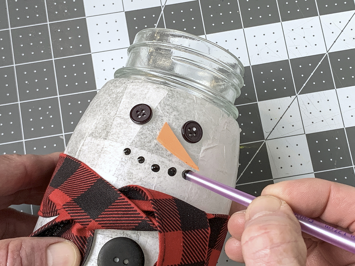 Dotting a snowman mouth using black paint and the end of the paintbrush