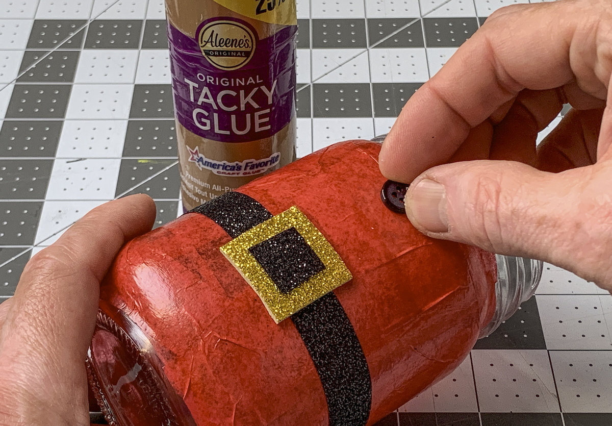 Gluing black buttons down to the front of the Santa mason jar