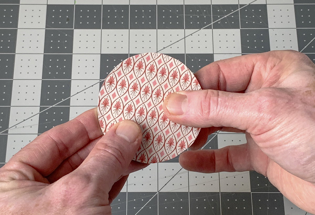 Smoothing the paper down onto the mason jar lid