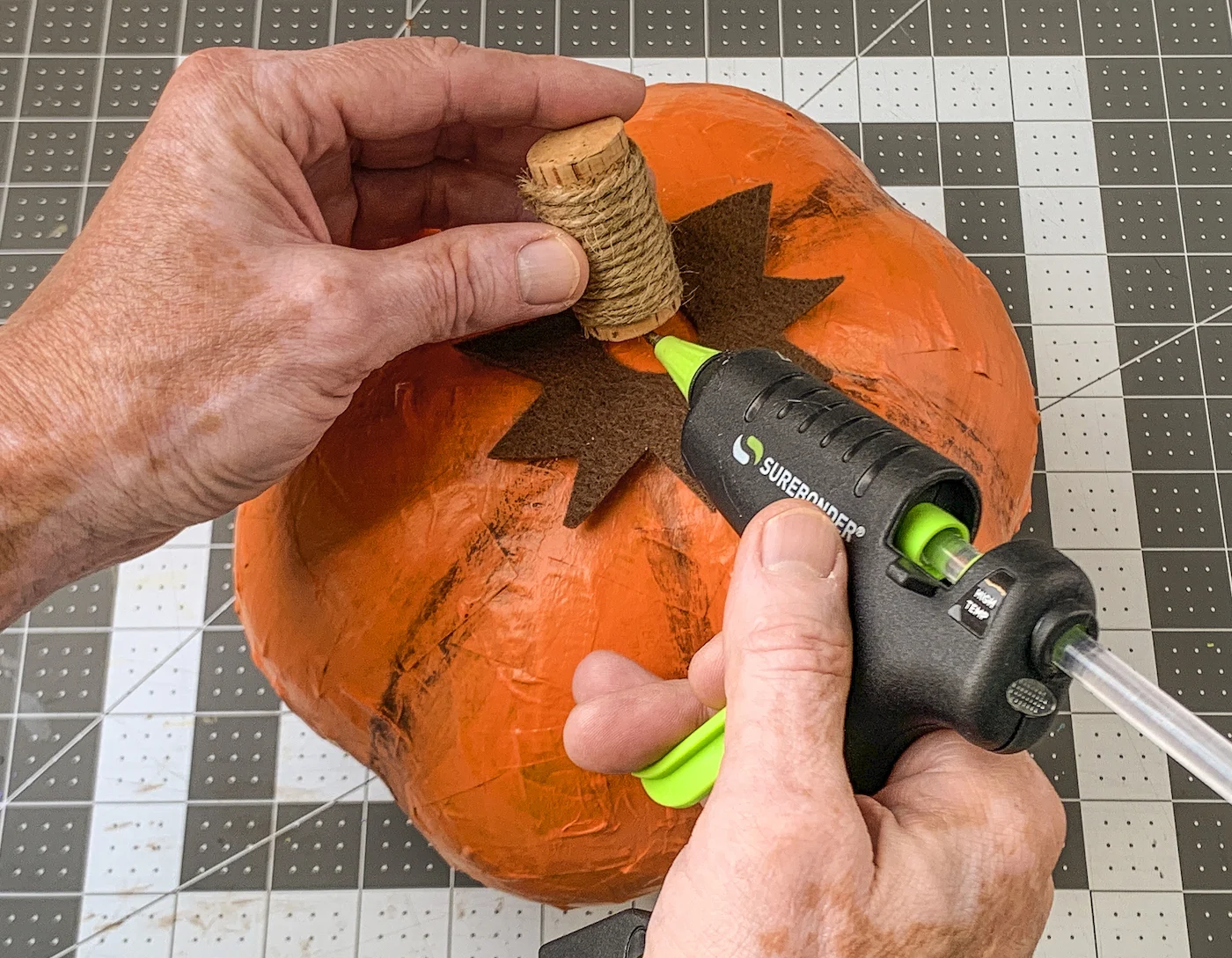 Hot gluing the wine cork to the top of the pumpkin