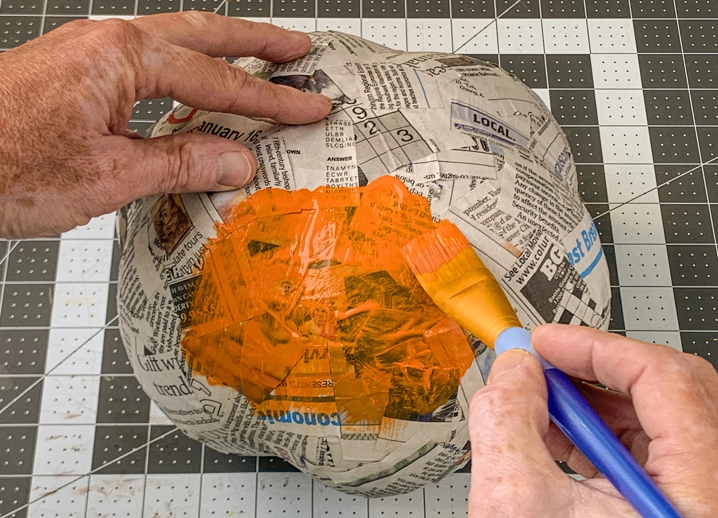 Painting a first layer of orange paint on the pumpkin