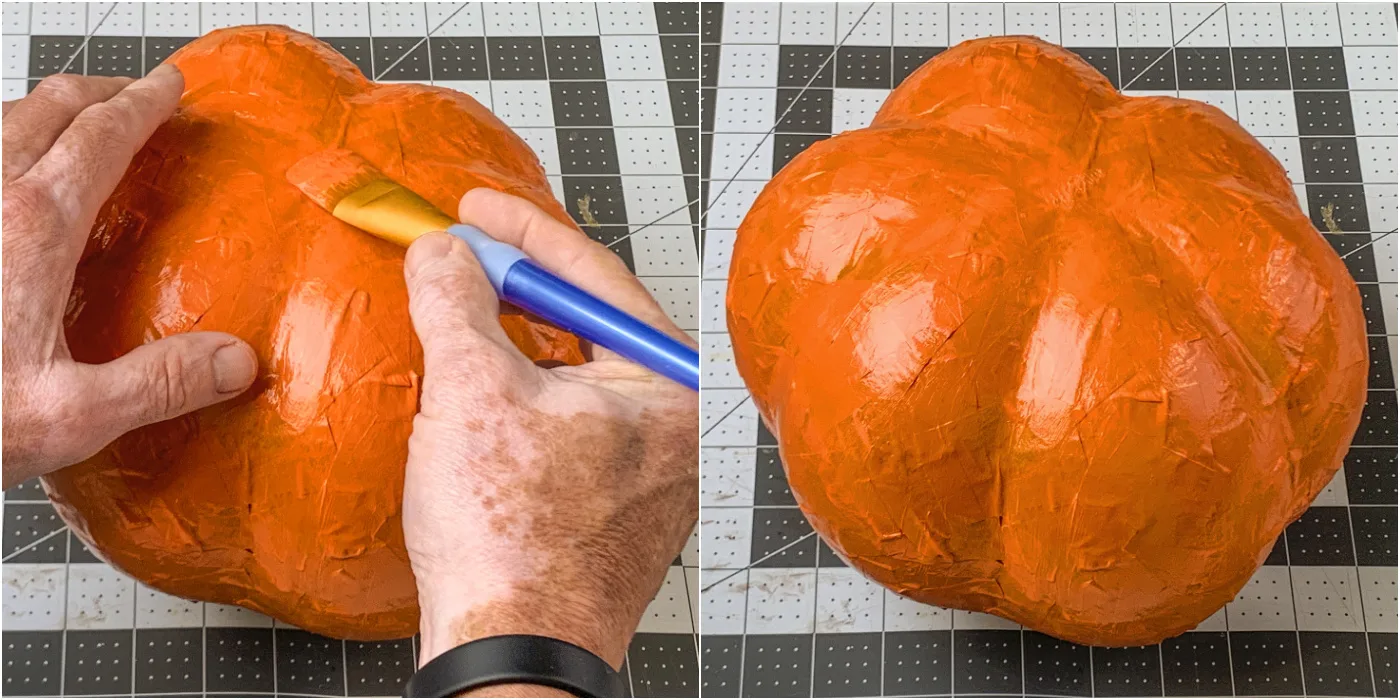 Painting two layers of orange paint on the paper mache pumpkin