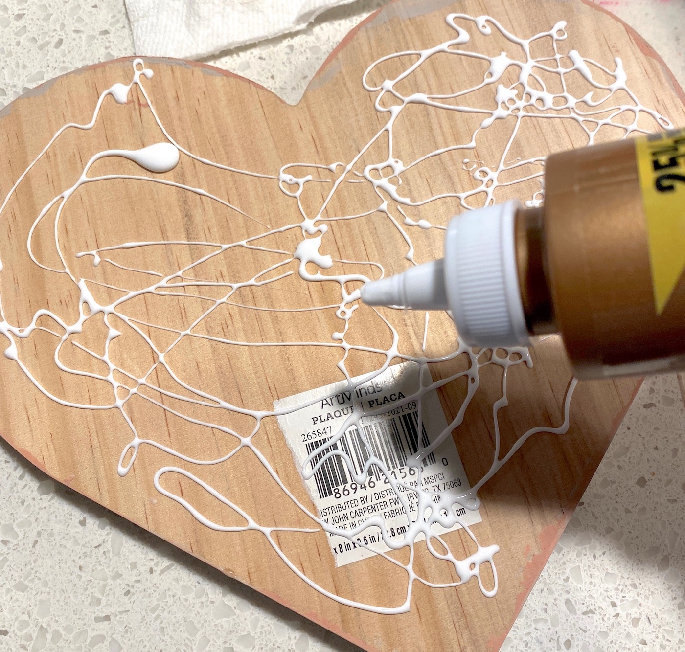 Applying glue to the back of the wood heart