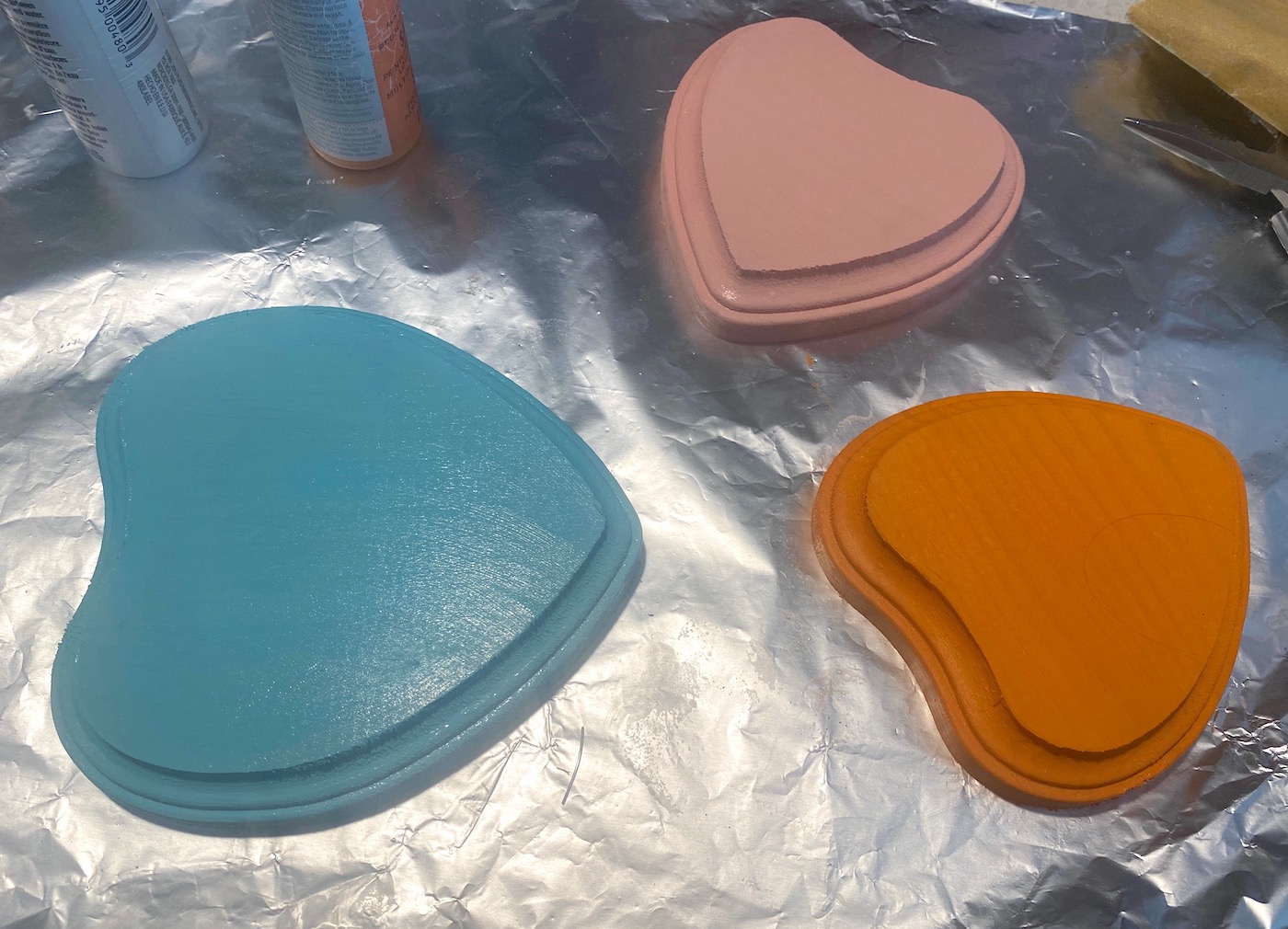 Three wood hearts painted with blue, orange, and pink