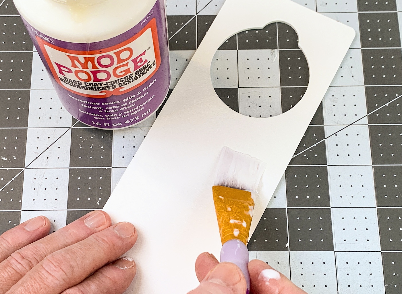 Applying Mod Podge to the top of the painted wood door hanger