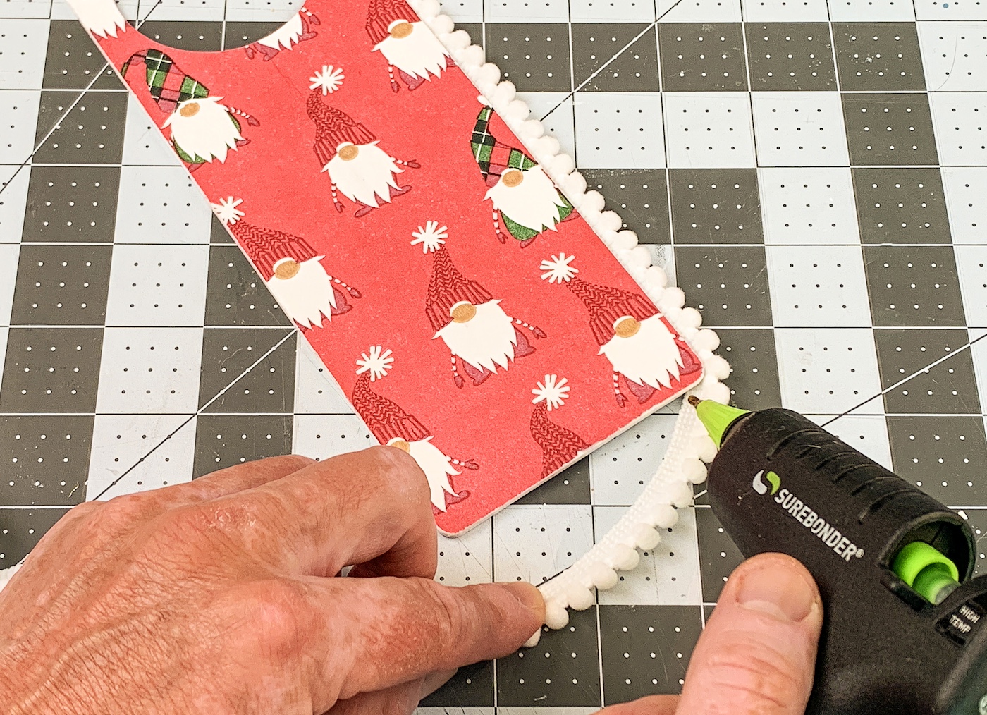 Hot gluing the trim around the edges of the wood door hanger