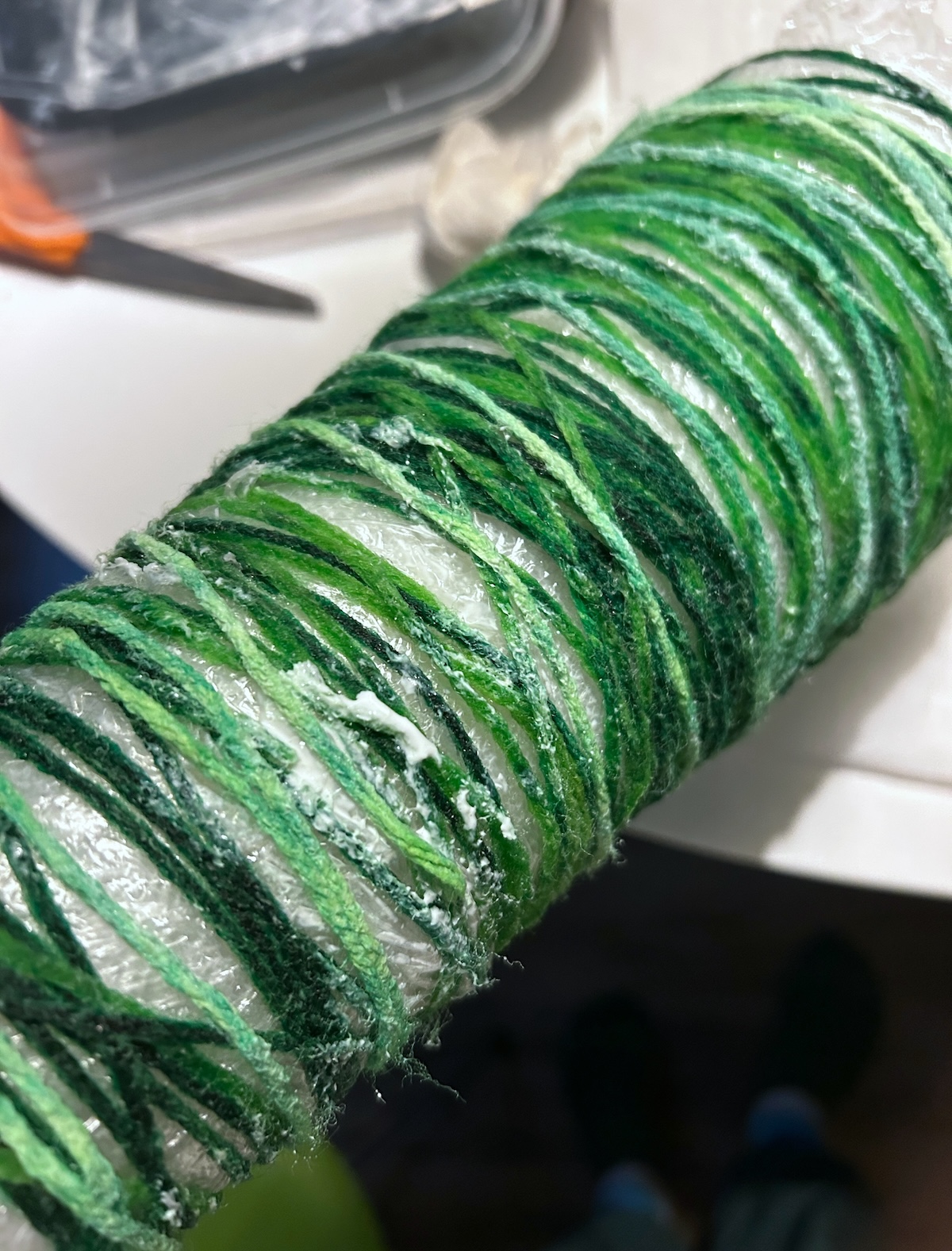 Additional pieces of green yarn wrapped on a cone