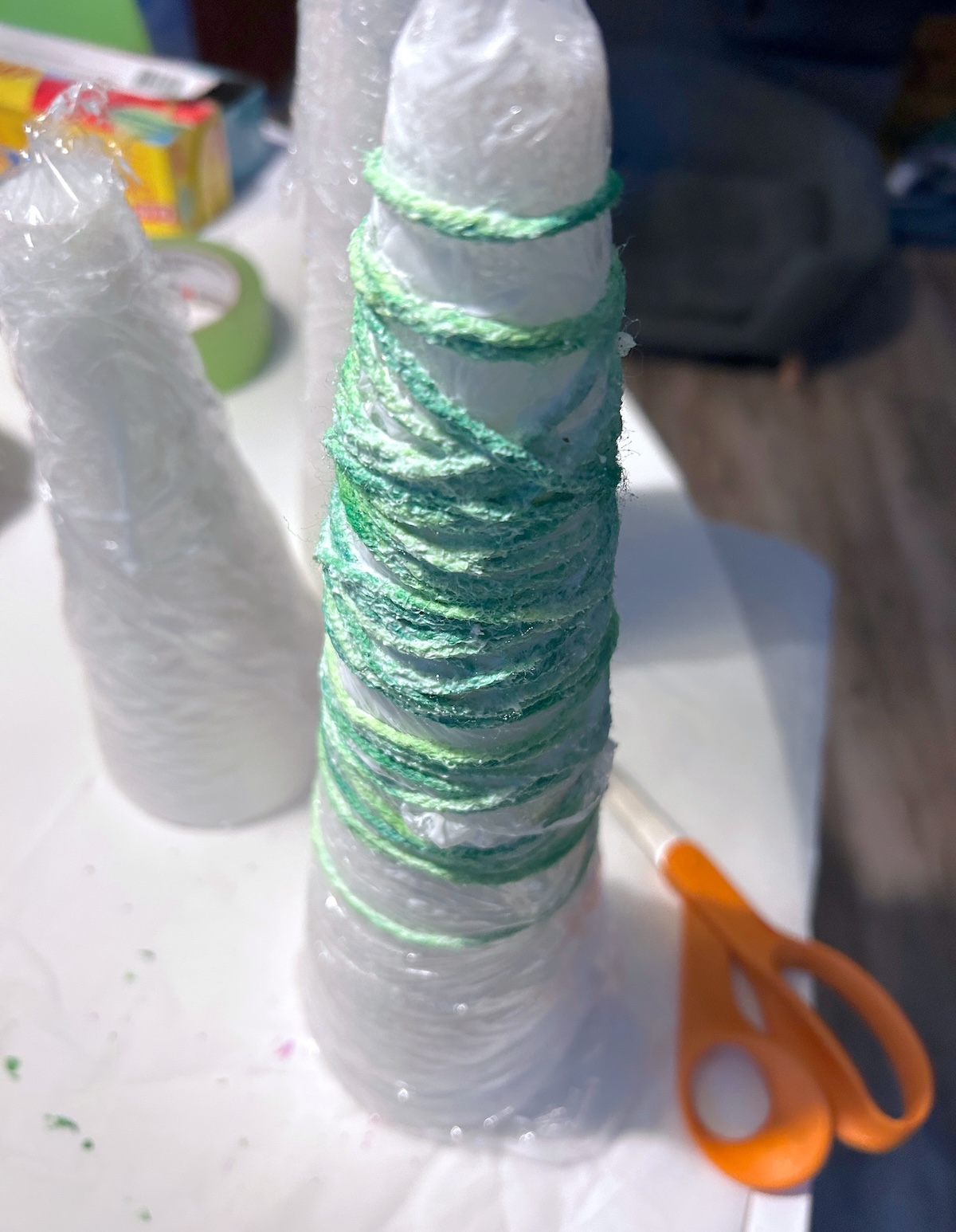 foam cone with plastic wrap and the first layer of yarn wrapped around it