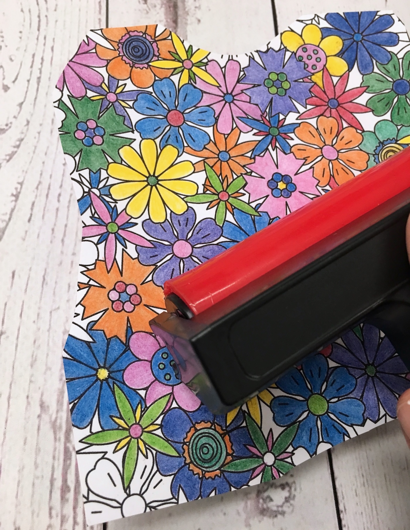 Applying a brayer to the top of the coloring page on the wood letter