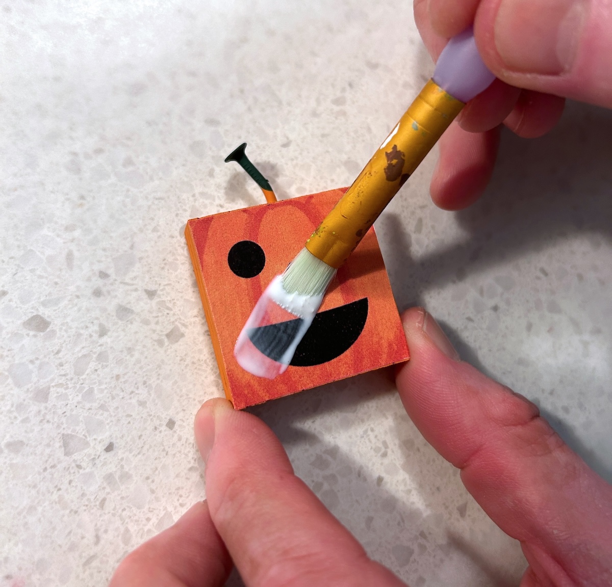 applying mod podge to the pumpkin face
