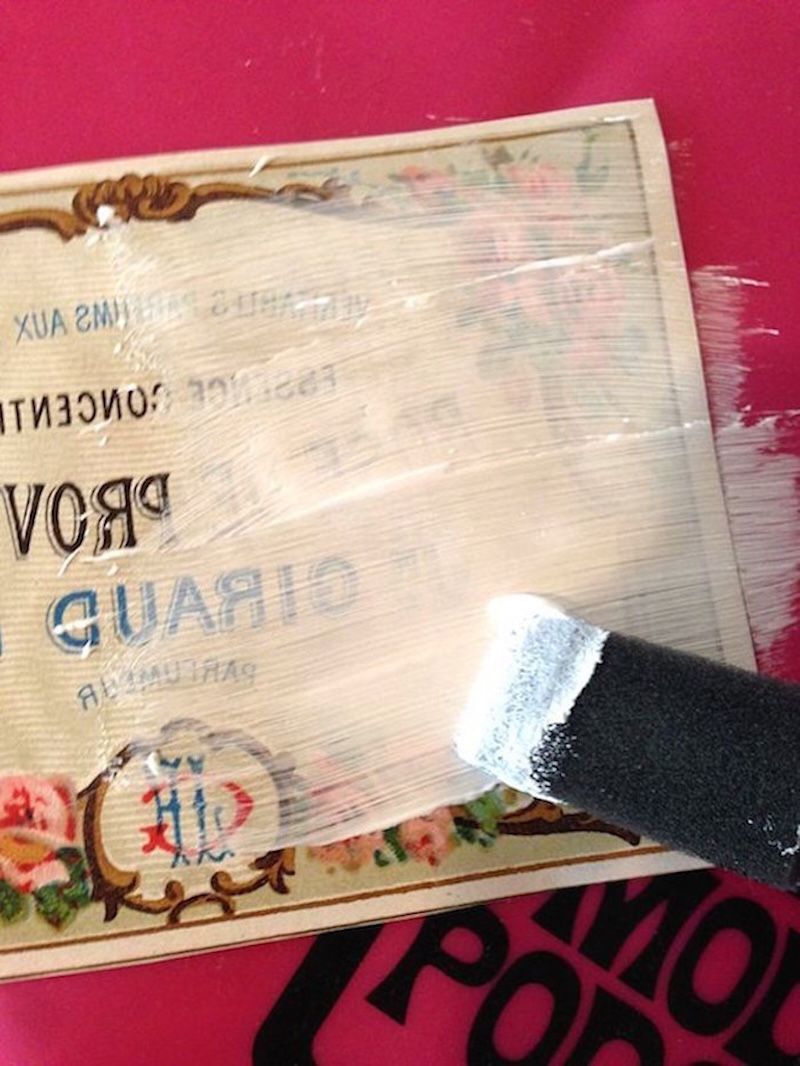 Applying Mod Podge photo transfer medium over an image with a foam brush