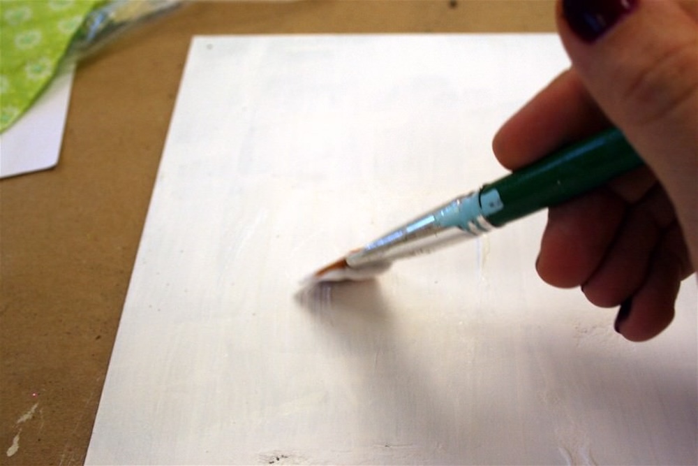 Applying Mod Podge to the white background with a brush