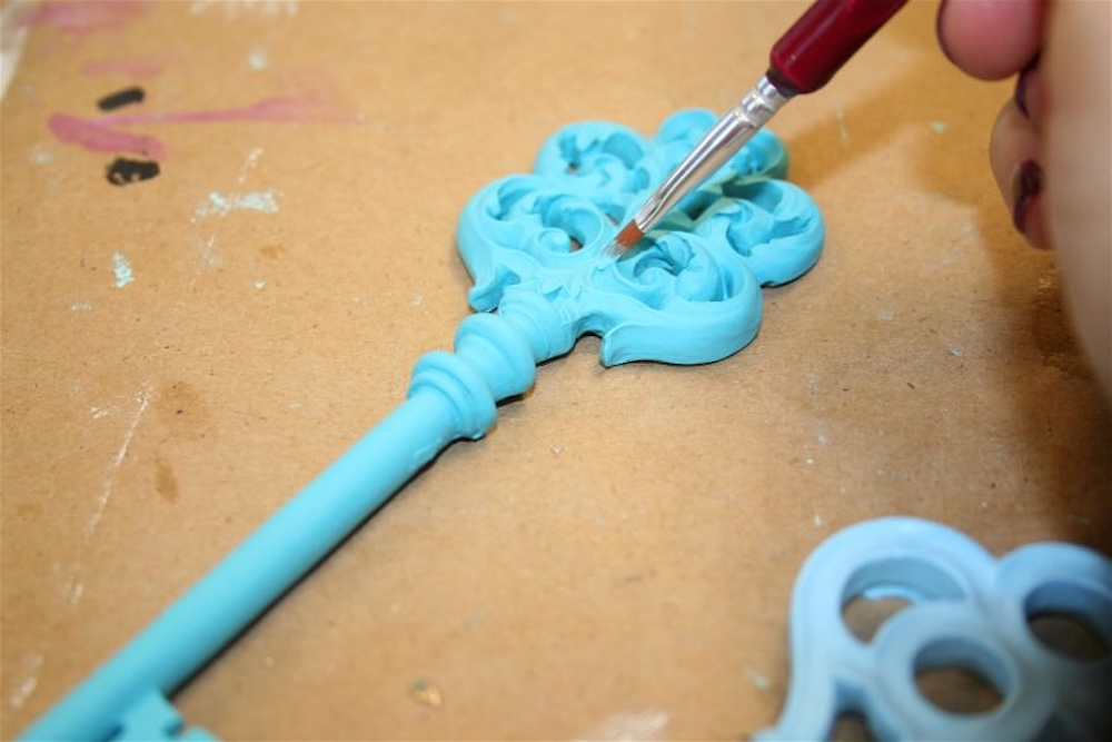 Painting the grooves of the faux key with a small paintbrush